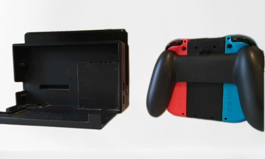 Nintendo Switch s tabletem v dokovací stanici a Joy-Cony v Joycon Gripu zezadu