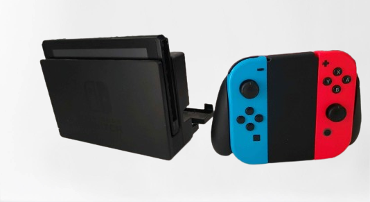 Nintendo Switch s tabletem v dokovací stanici a Joy-Cony v Joycon Gripu zepředu
